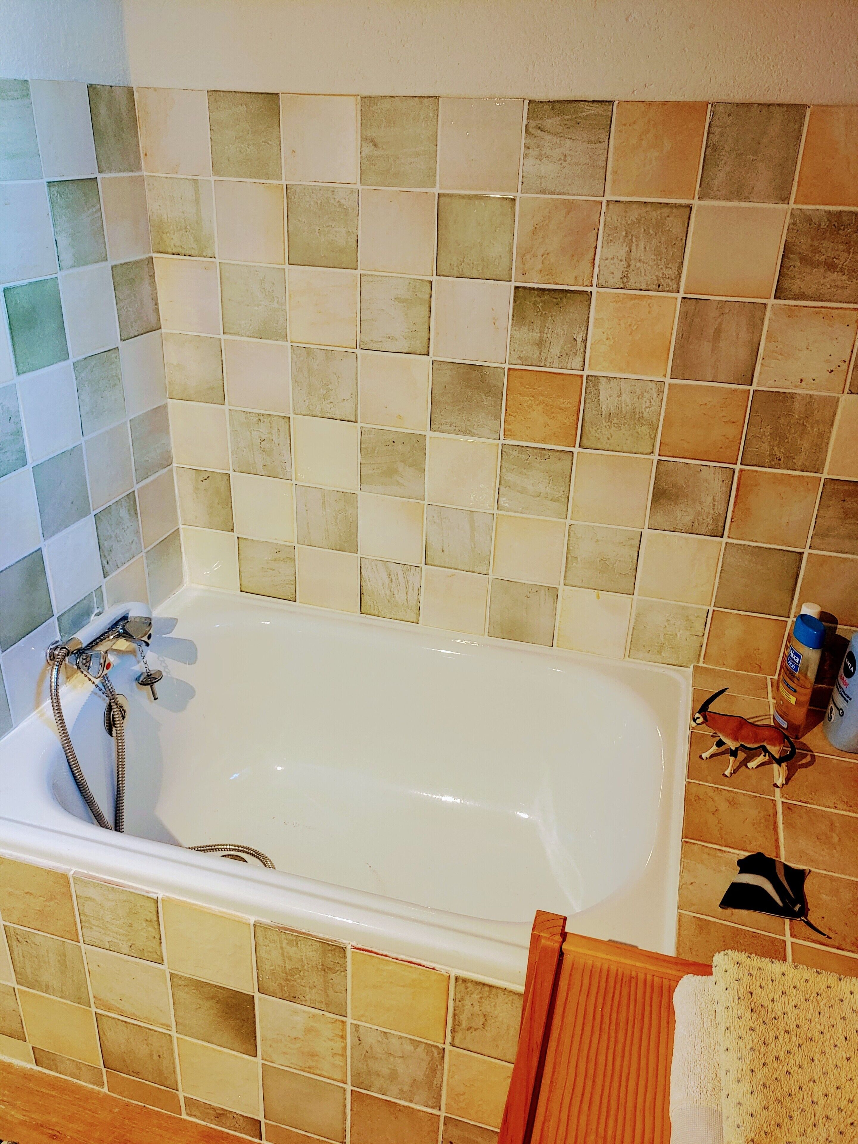 A bathtub with a shower head, tiled walls, and a towel rack.