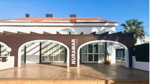 Un edificio con un cartel que dice "NURAMAR" y un área de entrada con baldosas.