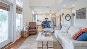 A spacious living room with a large window, a cozy fireplace, and a comfortable seating area. - Steps to pool/gated community-4 free bikes-beach toys-backyard/now 2 king beds  (Santa Rosa Beach)