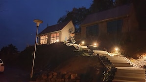 Ein Haus mit geneigtem Dach, großen Fenstern und einer Treppe zum Eingang.