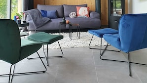 Ein gemütliches Lodge-Interieur mit Holzwand, einer Couch, einem Fernseher und einem Kamin.