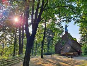 A stone building with a pointed roof and a blue steeple, surrounded by trees and a picnic table. - Odenwald Lodge with infrared sauna and "Haus Himmelblau" e-charging station (Reichelsheim)