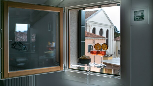 Ein Fenster mit Blick auf ein Gebäude mit weißer Fassade und Rundbogenfenstern.