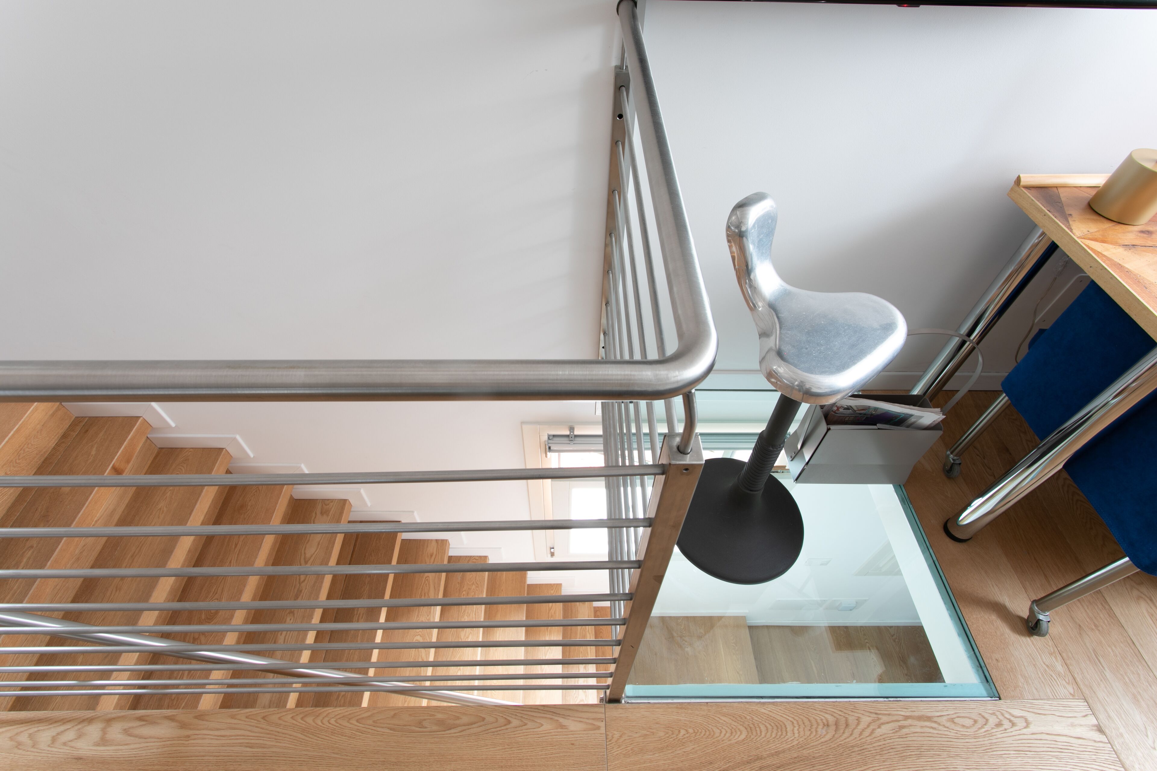 Un escalier moderne doté d’un plancher en verre, de rampes en métal et d’une finition en bois.