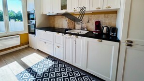 A modern kitchen with white cabinets, a black countertop, and a patterned rug.