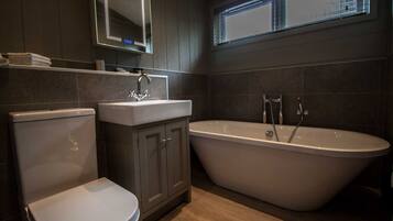 A modern bathroom with a freestanding bathtub, a toilet, and a vanity with a mirror.