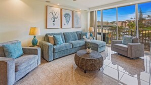 A spacious living room with a large sofa, a round coffee table, and a ceiling fan. - Where Haleakala Meets the Sea Kihei Remodeled Oceanfront Condo Rooftop BBQ (Kihei)