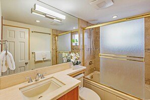 Un baño con un espejo grande, un lavabo, un inodoro y una ducha.