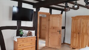 Une pièce comprenant une commode en bois, un téléviseur fixé au mur et une armoire en bois.