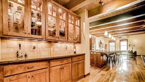 Un'ampia cucina con mobili in legno, un piano di lavoro in marmo e un angolo bar con sgabelli.