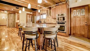 Un'ampia cucina con mobili in legno, un'isola centrale con sgabelli ed elettrodomestici moderni.