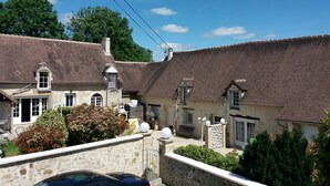 A traditional stone building with a tiled roof, a stone wall, and a car parked in front. - Gîte in the heart of the Perche, Le Percheron (Perche-en-Nocé)