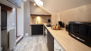 A modern kitchen with a built-in microwave, a fruit bowl on the counter, and a dishwasher. - Gîte in the heart of the Perche, Le Percheron (Perche-en-Nocé)