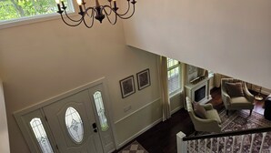 A spacious living area with a chandelier, a fireplace, and a view of the outdoors through large windows. - Name: Hill Crest<br>Private Setting. Heated Pool. 4 Minutes to Dreams Park  (Cooperstown)