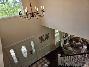 A spacious living area with a chandelier, a fireplace, and a view of the outdoors through large windows.