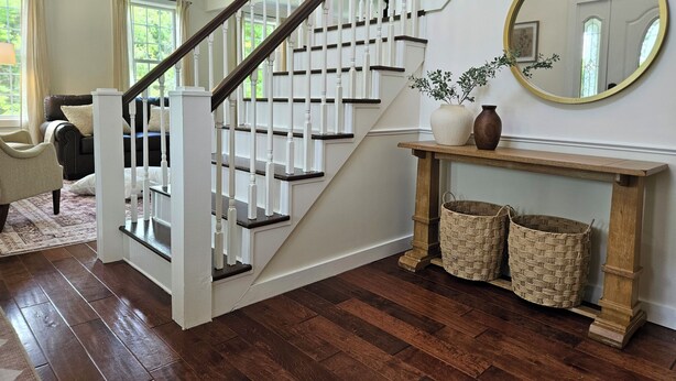 A staircase with white railings and dark wood steps, a ceiling fan, a mirror, and a console table with baskets. - Name: Hill Crest<br>Private Setting. Heated Pool. 4 Minutes to Dreams Park  (Cooperstown)