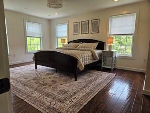 A bedroom with a bed, a nightstand, a rug, and framed artwork on the wall.