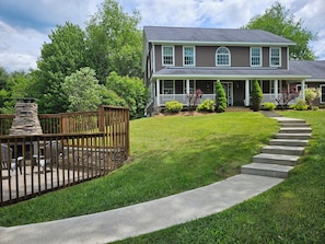 A two-story house with a stone fireplace, a front porch, and a well-maintained lawn.