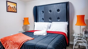 A neatly made bed with a dark headboard, white pillows, and an orange throw blanket. - Exquisite & Cozy La'Posh Suite w/WiFi, Workspace, Storage (Airdrie)