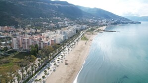Eine Küstenstadt mit Strand, Gebäuden und einem Berg im Hintergrund.