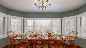 A dining room with a large wooden table set for six, surrounded by six wooden chairs.