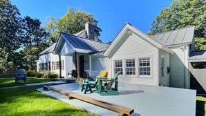 A house with a large deck, a covered outdoor seating area, and a well-maintained lawn.