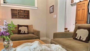 A living room with two sofas, a fur rug, and a vase with flowers.