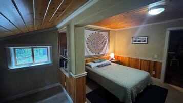 Une chambre à coucher avec un lit, une fenêtre, une tapisserie et une porte donnant sur une autre pièce.