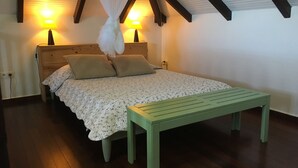 A bedroom with a bed, bedside lamps, a bench, and a canopy. - Villa COLORADO - GdF - ANSE FIGUIER (TERRE DE HAUT)