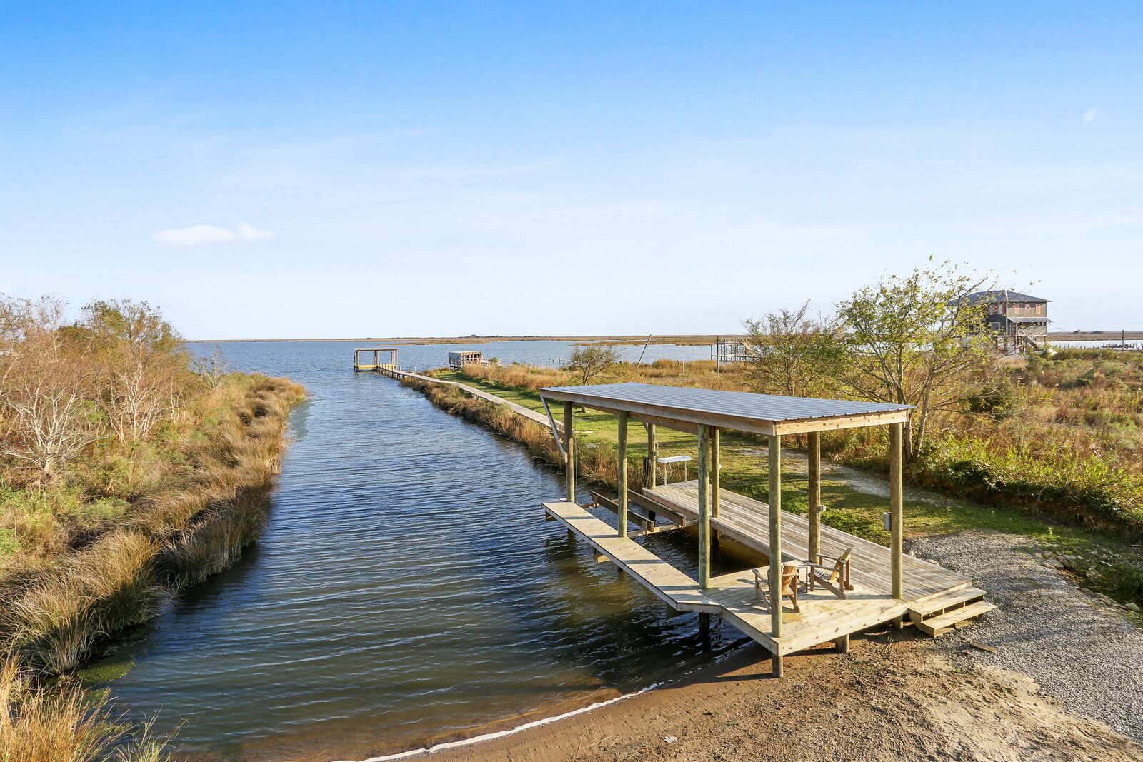 Eine Holzstege, der sich in ruhiges Wasser erstreckt, mit einem überdachten Sitzbereich an einem Ende.
