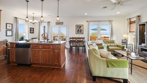 A spacious living area with a large sofa, a dining table, and a kitchen with a central island.
