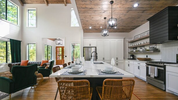 A spacious kitchen with a large island, white cabinetry, and a black backsplash.
