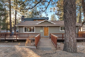 A cabin with a wooden deck, a front door, and a small porch.