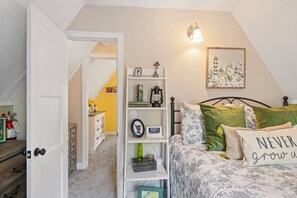 A bedroom with a bed, a nightstand, a shelf with decorative items, a wall clock, and a framed picture. - An amazing cottage that takes you back to childhood tales (Big Bear Lake)