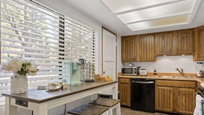 Una cocina compacta con armarios de madera, un microondas, una cafetera y un lavavajillas.