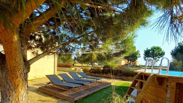 A pool area with sun loungers and a wooden deck.