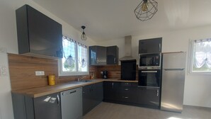 A modern kitchen with dark cabinetry, a dishwasher, a microwave, and a refrigerator.