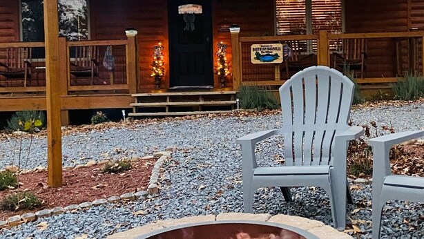 A rustic cabin with a fire pit, outdoor seating, and a sign indicating a restaurant.