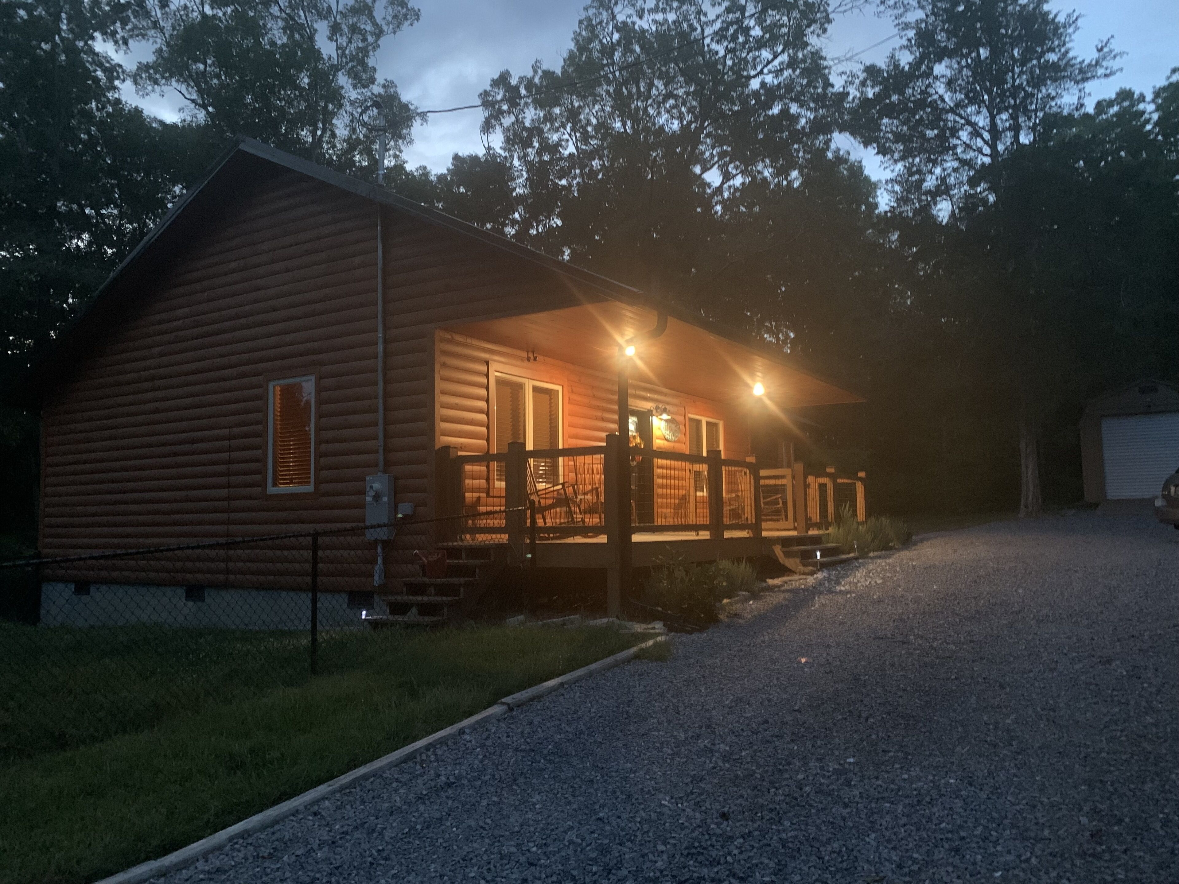 Une cabane en rondins avec un porche et un garage.