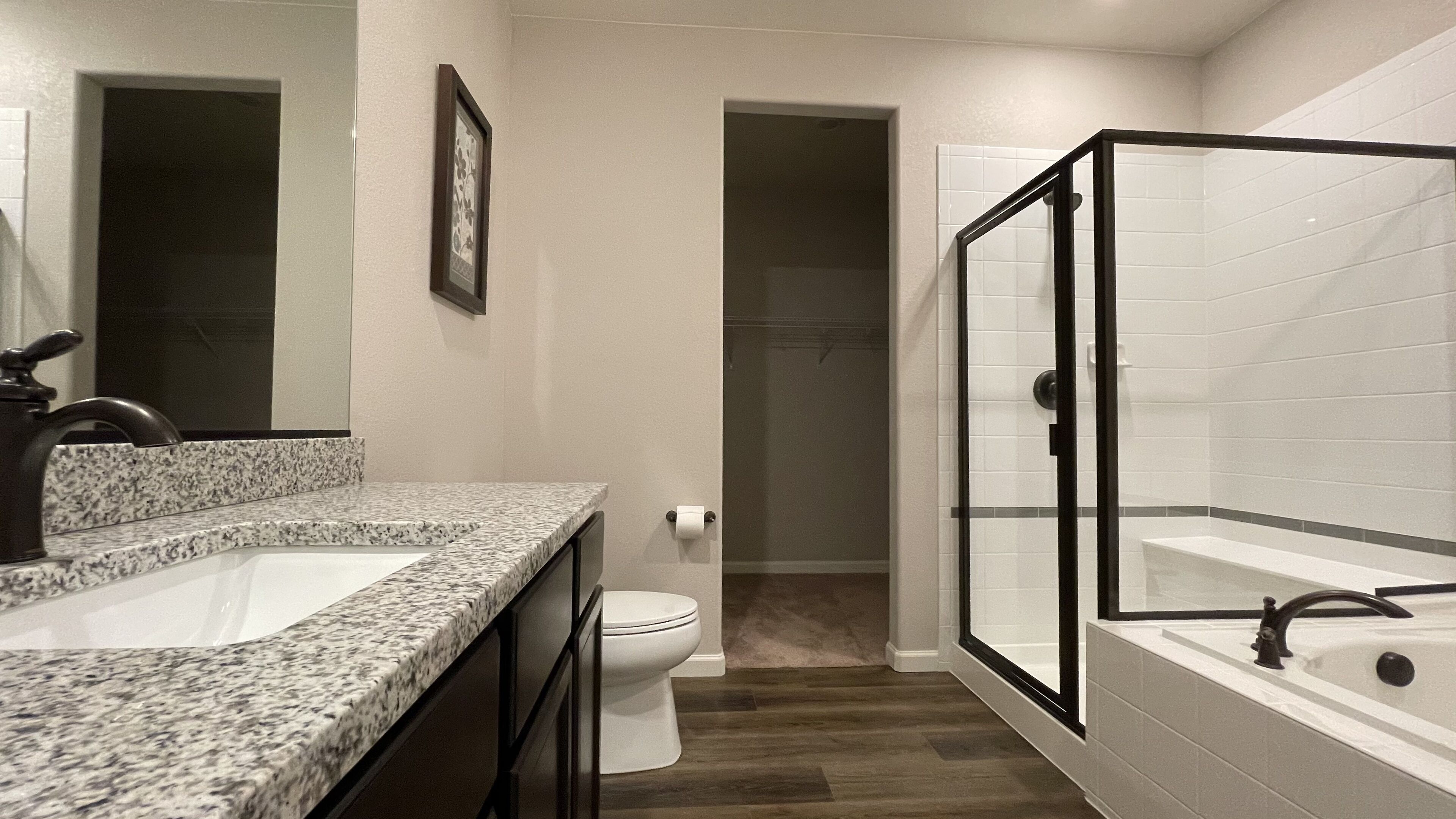 Une salle de bain avec un lavabo sur un plan de travail en granit, des toilettes, une douche à parois de verre et une baignoire.