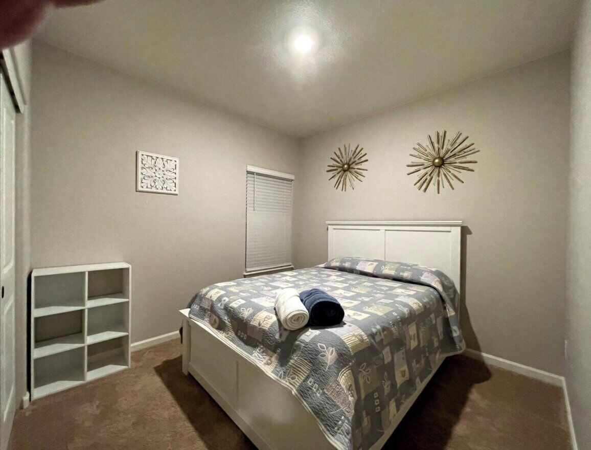 Un dormitorio con cama, una estantería empotrada y decoración mural.