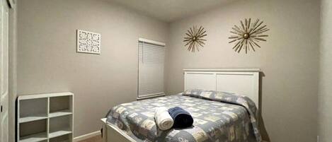 Un dormitorio con cama, una estantería empotrada y decoración mural.