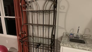 Una cocina con encimera de granito, pileta de acero inoxidable y escurreplatos metálico.