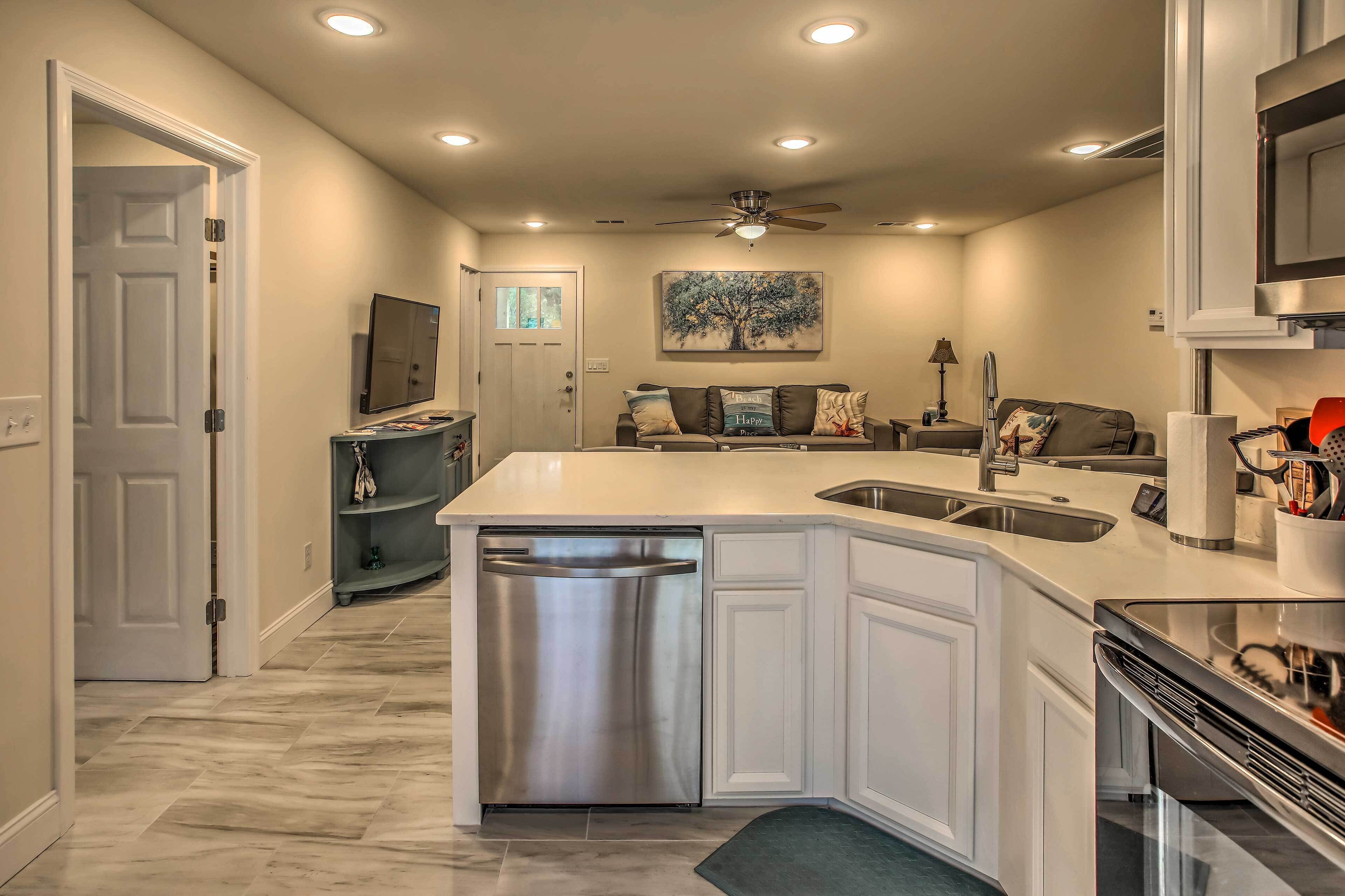A modern kitchen with a built-in dishwasher, a dining area with a sofa, and a ceiling fan.