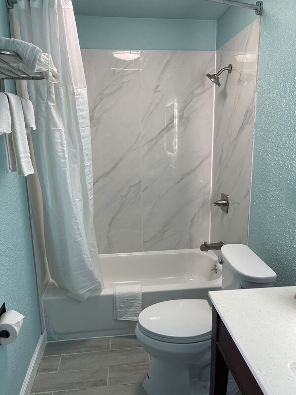 A bathroom with a bathtub, toilet, and sink.