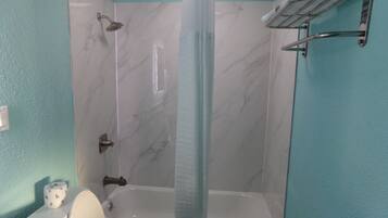 Une salle de bain avec une baignoire, une douche et des toilettes.