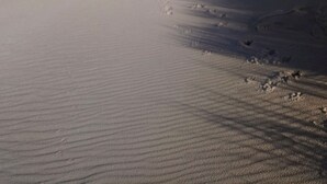 Una playa con cielo despejado y olas suaves.