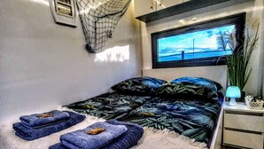 Un dormitorio con cama, televisión, mesita de noche y ventana con vistas.