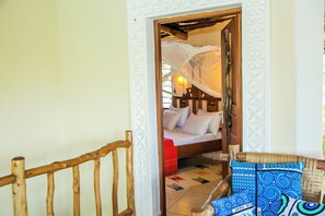 A bedroom with a wooden bed, a red blanket, and a canopy. - 3 Bed Cottage Sleeps 6- Pool, Chef Option, Parking (Diani Beach)