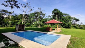 A rectangular swimming pool with a red-roofed pavilion nearby. - Cozy villa surrounded by nature with AC & pool (La Fortuna)